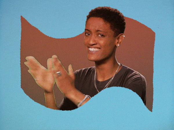 Celebrity gif. Framed in a flag shaped opening on a pale blue background, Syd Tha Kid claps and points at us.