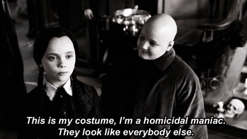 Movie gif. Christina Ricci as Wednesday Addams in The Addams Family says, “This is my costume, I’m a homicidal man. They look like everybody else.” While she says this, Jimmy Workman as Pugsley dressed as Uncle Fester looks at her sister with a smile.