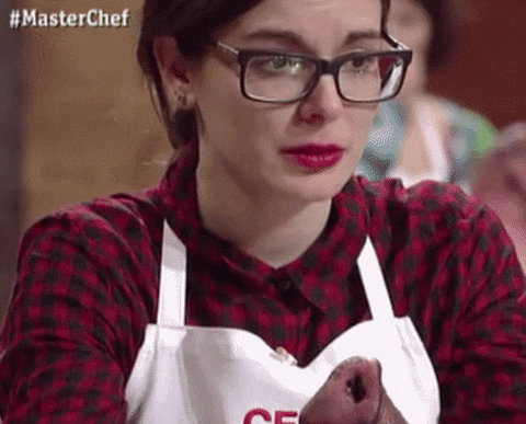 TV gif. Woman on Master Chef wearing glasses and an apron holds back tears as we zoom in on her sad face.
