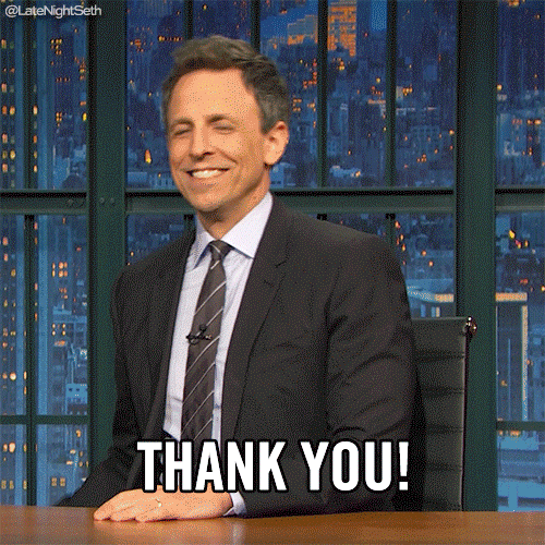 Late Night gif. TV host Seth Meyers grins as he pulls a bullhorn from under his desk then says into it, "Thank you."