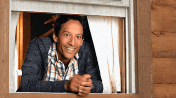 TV gif. Danny Pudi, as Tim in The Guest Book leans out a window and waves with a friendly smile.