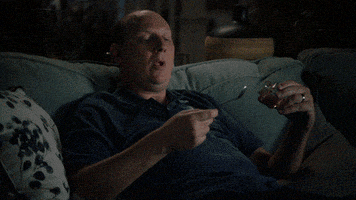 TV gif. Dan Bakkedahl as Tim Hughes on Life in Pieces sits in a dark living room on the couch. He looks down at the spoon and a snack in his hands, and says “I'm so fat.” He then jerks his head like he’s waking himself up and looks around in shock. He says, “Who said that?”