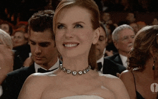 Celebrity gif. A smiling Nicole Kidman, seated at the Oscars, shrugs off a compliment with false modesty.