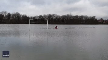 Man Paddles Kayak Through Flooded Soccer Field in Manchester
