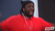 Reality TV gif. A Rapper on The Rap Game jumps around excitedly, waving his hands in the air. He smiles widely and looks around with wide eyes.
