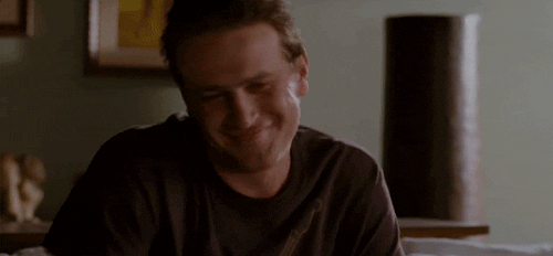 Movie gif. Jason Segel as Peter in Forgetting Sarah Marshall smiles, raises his hands and shrugs as if to say "I don't know!"