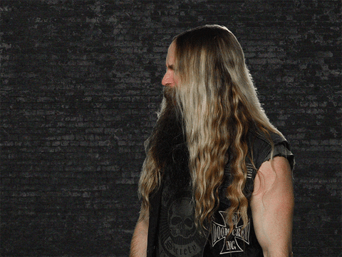 Celebrity gif. Tilting his head to the side, Zakk Wylde slowly turns his face toward us, squinting and confused.
