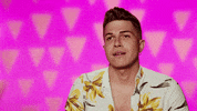 Reality TV gif. Alyssa Hunter on RuPaul's Drag Race sits out of drag for an interview in front of a pink background, giving a quick sassy side eye, raising his eyebrows and pursing his lips as if unimpressed.