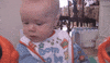 Video gif. A baby's blank facial expression cracks into a deeply confused smile.
