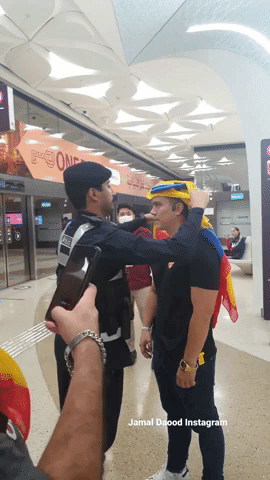 Policeman Adjusts Ecuadorian Fan's Headscarf