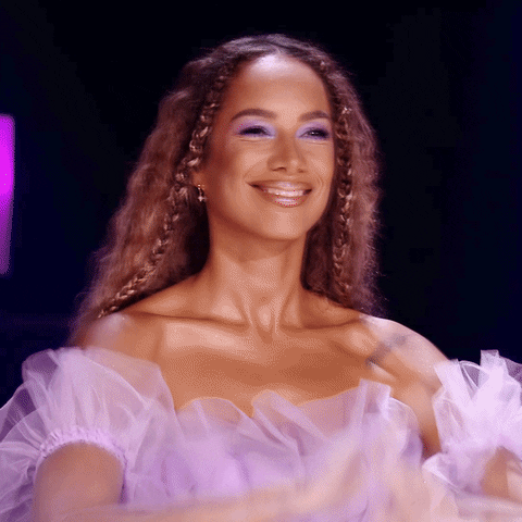 Celebrity gif. Leona Lewis smiling and clapping, raises her hands up in tempo with a groovy rhythm, dancing along.
