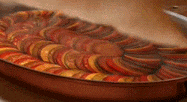 Disney gif. Remy from Ratatouille opens up his pan to show the perfect ratatouille he's made. He plates it and adds sauce on the side as it steams and looks delicious.