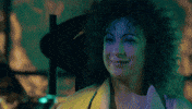 TV gif. Alex Kingston as River Song from Doctor Who smiles at us and raises a glass of champagne.