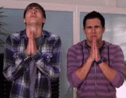 Video gif. Two young men stand side by side. Their eyes closed and their hands in prayer as if pleading with someone.