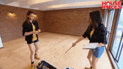 Reality TV gif. Two contestants on House Rules are measuring their home and one of them pulls a measuring tape out and holds it above her head.