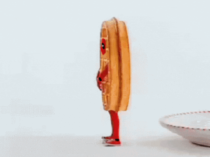 Video gif. A person wearing a giant waffle costume falls backwards onto a giant plate before being promptly covered in a pat of butter and a slosh of sticky syrup.