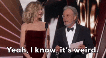 Nodding his head and spreading his hands, Billy Crystal says “Yeah, I know, it’s weird.” Meg Ryan stands next to him, first watching him and then smiling.