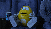 Ad gif. A yellow M&M looks around in fear and leaps out of their seat in the theater saying, "I'm out!"