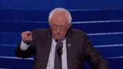 Political gif. Bernie Sanders at the Democratic National Convention leans over a microphone and points out at the crowd. He laughs as he nods his head and then gives a quick thumbs up, laughing harder.