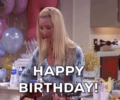Friends gif. Lisa Kudrow as Phoebe bounces and looks around as she plays her guitar in a room full of balloons. She happily sings, “Happy Birthday!”