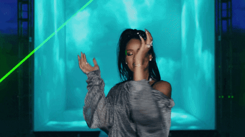 Celebrity gif. Rihanna claps her hands and dances toward us as lasers and lights flash around her.