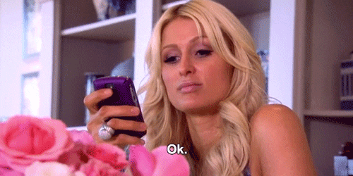 Celebrity gif. Paris Hilton looks at her Blackberry phone with a blank expression and says, "ok."