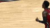 Sports gif. Miami Heat player Victor Oladipo runs onto the court, shakes hands and hugs a teammate who pats him on the back.
