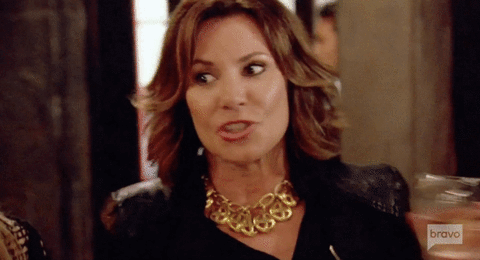 Reality TV gif. Luann de Lesseps from Real Housewives of New York grabs a wine glass and turns to the ladies, saying, "Cheers!" with a cheeky smirk.