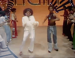 TV gif. Dancers on soul train boogie down a corridor formed by people lined up to the sides.