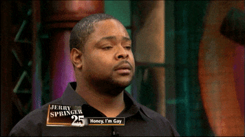 Reality TV gif. From The Jerry Springer Show, a man with his eyes closed jerks his head back, as if he just got slapped. Text, "Jerry Springer 25, Honey, I'm gay."