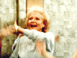 Video gif. Betty White with a wide smile on her face, waving her arms in front of her and jumping up and down like she's happy dancing with friends. 