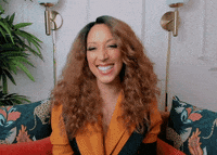Celebrity gif. Robin Thede smiles happily and claps her hands in gratitude.