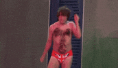 Movie gif. Mike Myers as Austin Powers. He has a speedo on that has the British Flag on it and his hairy chest is exposed. He dances as both arms flail in the air and he kicks his feet up.