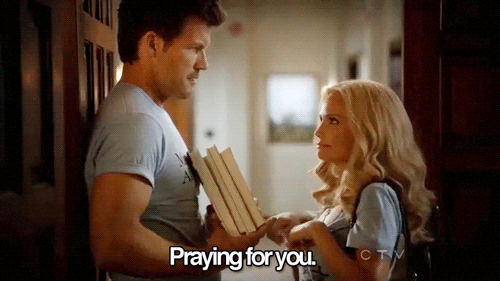 TV gif. Mark Deklin as Blake on GCB holds a stack of books and looks quizzically at Kristin Chenoweth as Carlene, who points at him cutely and smiles as she says, "praying for you," which appears as text.