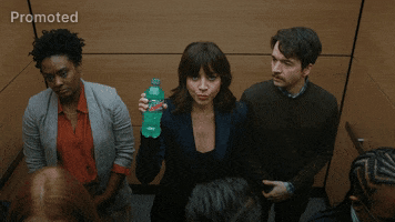Sponsored gif. Aubrey Plaza is wearing a suit and stands in the middle of an elevator with office workers. Suddenly, the elevator lights blink, dust falls and the elevator rattles. Everyone around her freaks out but she stares at us deadpan as she holds a Mountain Dew Baja Blast in her right hand, cocking her head and saying, "Having a blast."