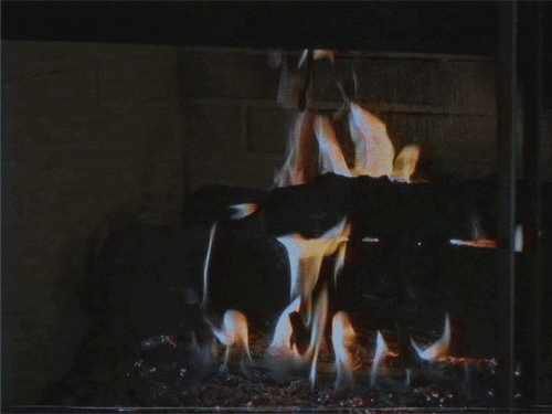 Video gif. Fire crackling over wood in a fireplace.