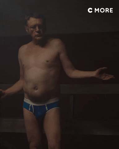 Video gif. An old man wearing nothing but a pair of blue briefs dances casually, holding a beer.