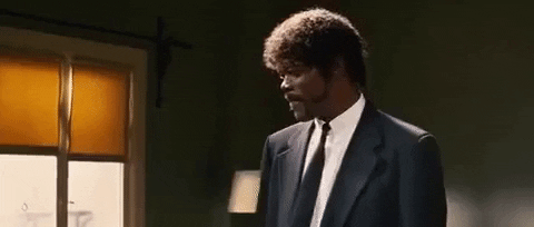 Movie gif. Samuel L Jackson as Jules in Pulp Fiction. He's standing in a room thinking and a smile stretches over his face as he figures it out. Then, he brings a hand to his mouth to stroke his chin gently.