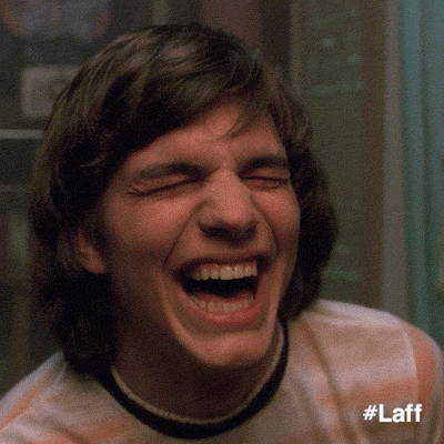 TV gif. Close up on Ashton Kutcher as Michael on That 70s Show. He is laughing hysterically, to the point where he’s rocking back and forth. 