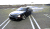 Video gif. A black Nissan Silvia s14 pulls donuts across a mostly-empty parking lot.