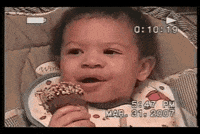 Video gif. In a home video dated March 31, 2007, a young baby grasps a Drumstick ice cream cone with a serious expression before bursting into laughter.