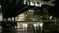 Video gif. A body of water under a bridge with a backdrop of a city, and the word 