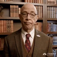 Ad gif. JK Simmons stands in front of an old-looking bookshelf, wearing a brown suit jacket, a red tie, and a small 