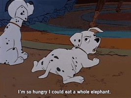 Disney gif. In 101 Dalmatians, a sitting puppy frowns while a puppy lying down looks over his shoulder and says "I'm so hungry I could eat a whole elephant," which appears as text.