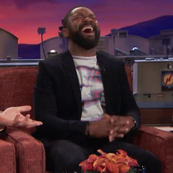 Celebrity gif. David Oyelowo sits in a chair as a guest on a talk show. He bursts into laughter, doubling over, before leaning back and bringing a hand to his mouth, still laughing boisterously.