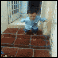 Video gif. Adorable toddler jumps down a couple of steps and stumbles toward us before giving us the middle finger.