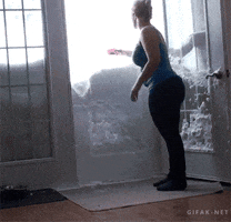 Video gif. Woman places a dish on top of a huge pile of snow at her front door; suddenly a white housecat bursts in through the bottom of snow pile.