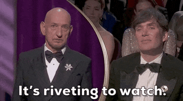 Oscars 2024 GIF. Split screen of Ben Kingsley speaking about Cillian Murphy and saying, "It's riveting to watch." Murphy stares on from the crowd with a small smile. 