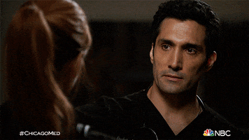 TV gif. Sarah Rafferty as Dr. Pamela and Dominic Rains as Dr. Crockett in Chicago Med. They both look distraught and Dr. Crockett loops an arm over Dr. Pamela, pulling her in for a hug.
