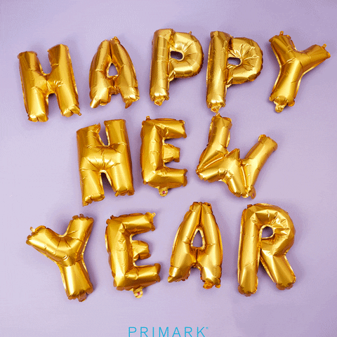 Stop motion gif. Pastel confetti rains down on gold mylar balloons that spell out, "Happy New Year."